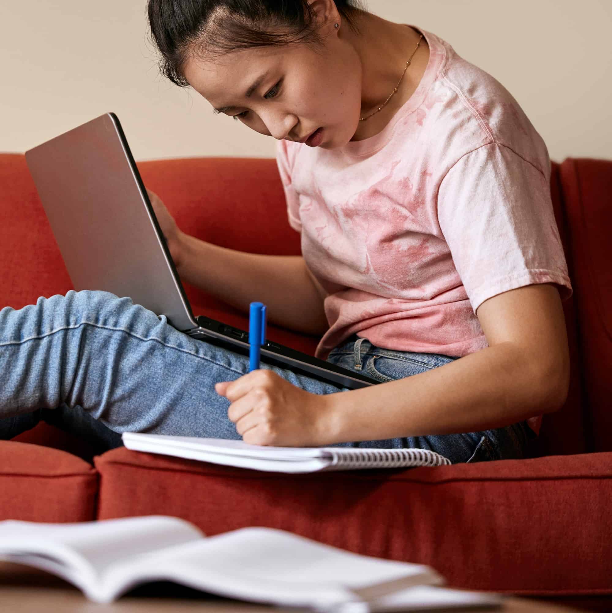 Student writing notes on couch